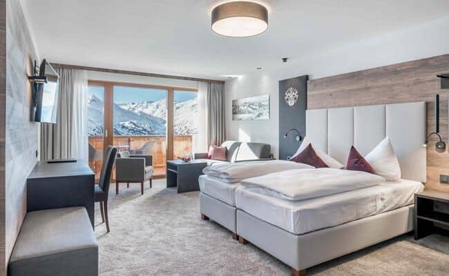 Primary bedroom with twin beds, work desk, and mountain-view balcony