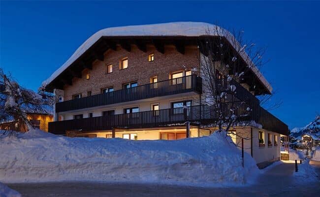Multi-story chalet exterior with wrap-around balconies and heavy snow