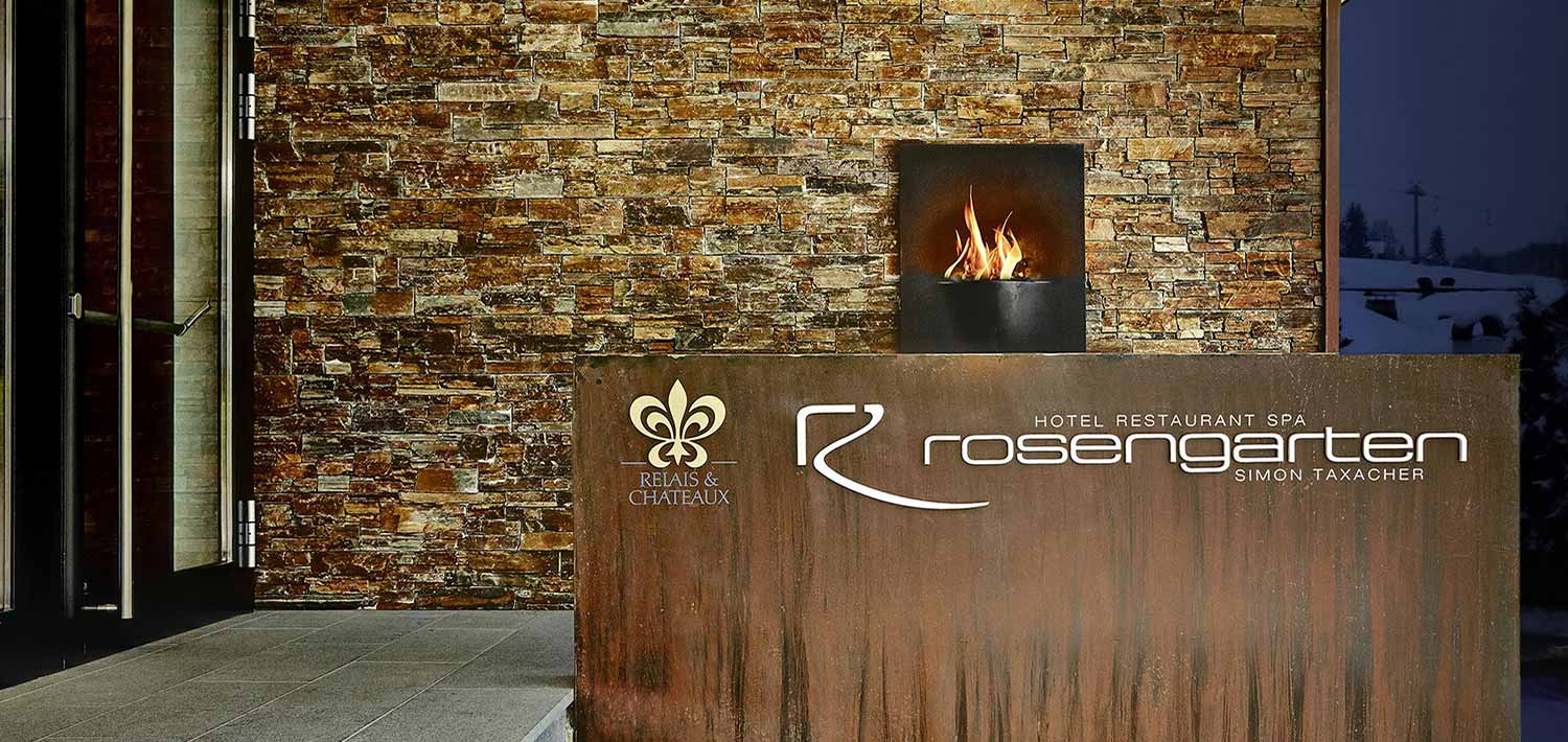 Hotel entrance with stone facade, outdoor fireplace, and Relais & Chateaux branding