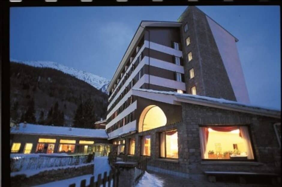Lodge exterior with stone facade and snow-covered mountain backdrop