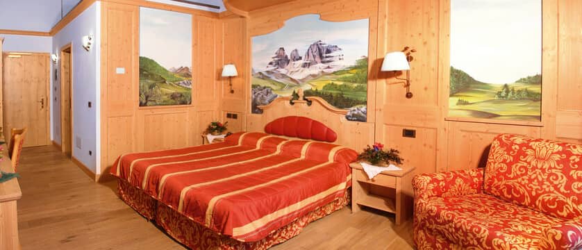 Guest suite with king bed, armchair seating, and mountain landscape murals