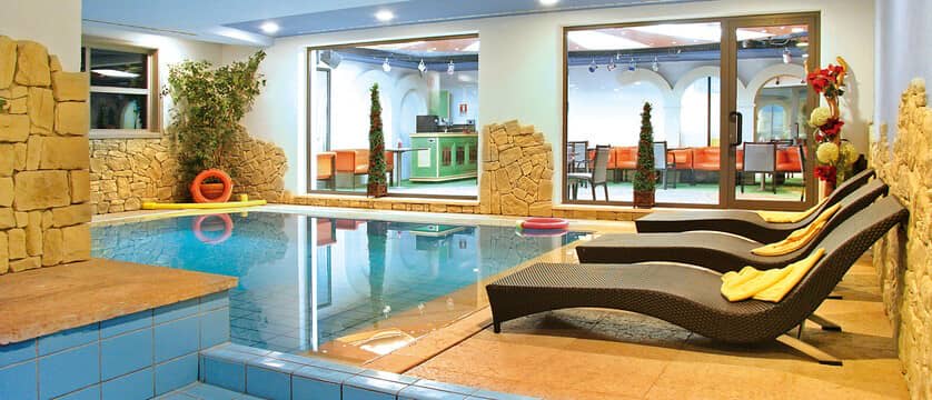 Indoor pool with poolside loungers and views of the garden bar