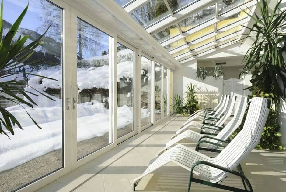 Glass-enclosed sunroom with heated tile floors and lounge seating for five