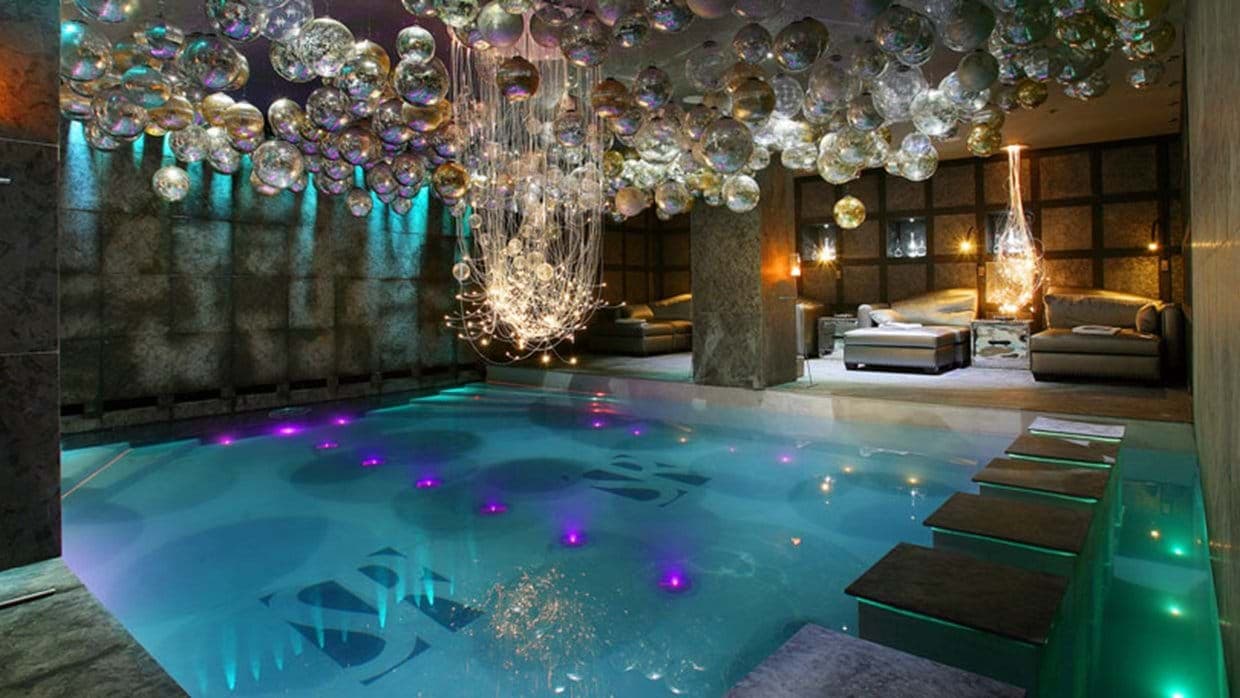 Indoor pool with underwater LED lighting and poolside lounge seating