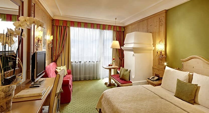 Bedroom with king bed, workspace, and traditional alpine tile stove