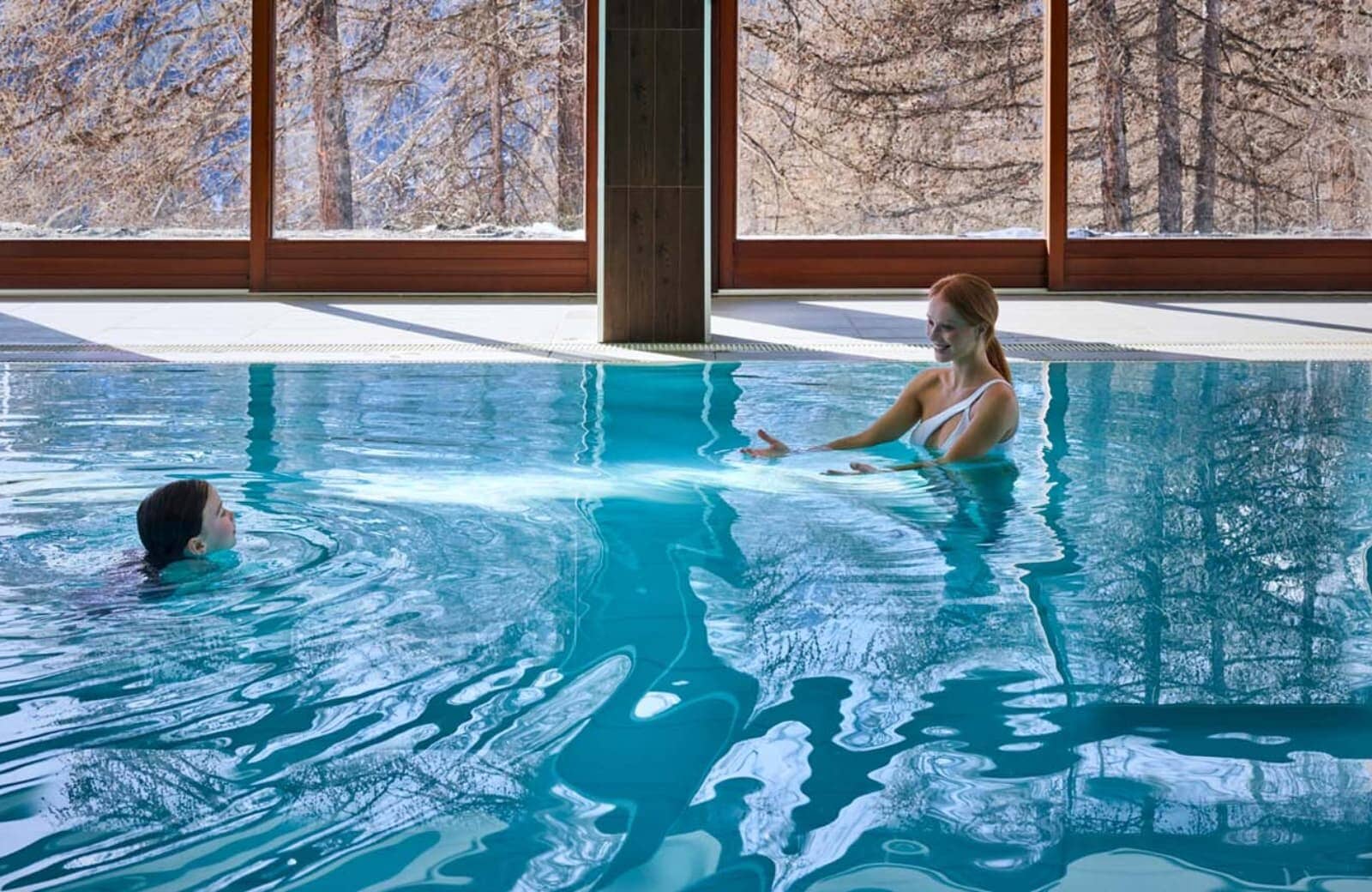 Indoor heated pool with floor-to-ceiling forest views