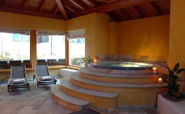Indoor heated spa with circular hot tub and poolside lounge chairs