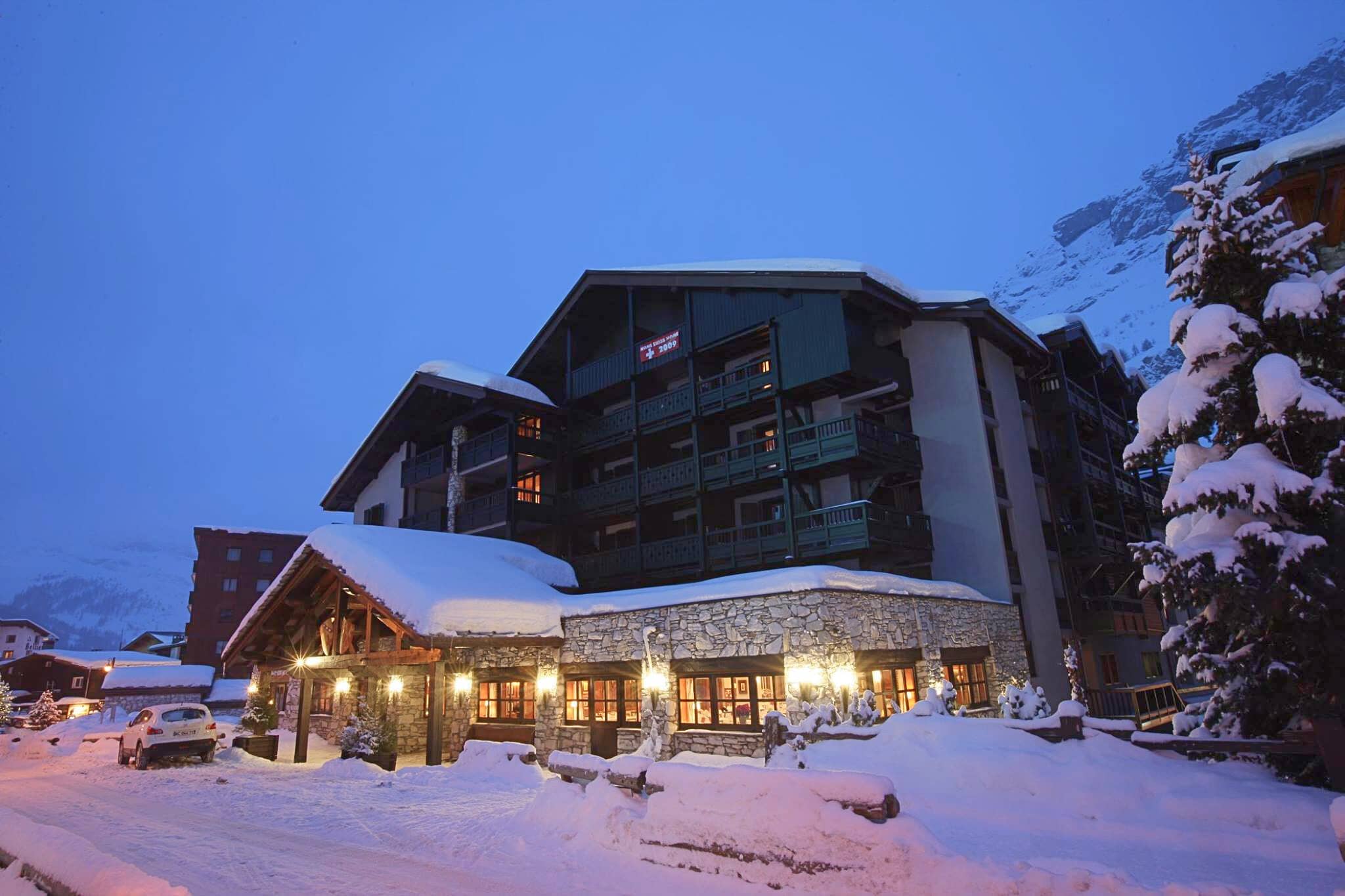 Ski-in lodge exterior with private balconies and mountain cliff backdrop