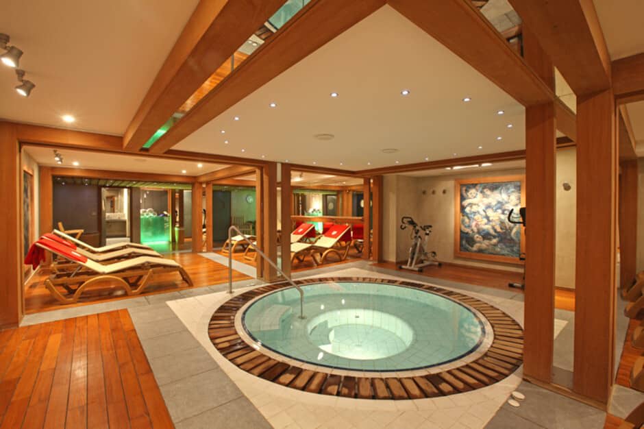 Indoor wellness area with circular whirlpool tub, loungers, and exercise bike