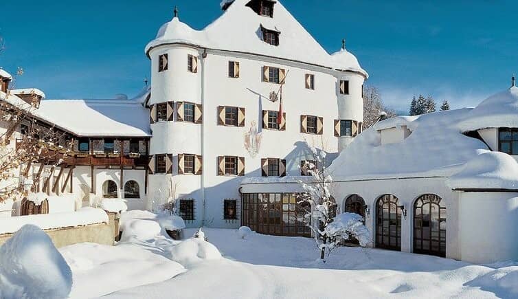 Snow-covered historic castle exterior with traditional wood shutters and turret towers
