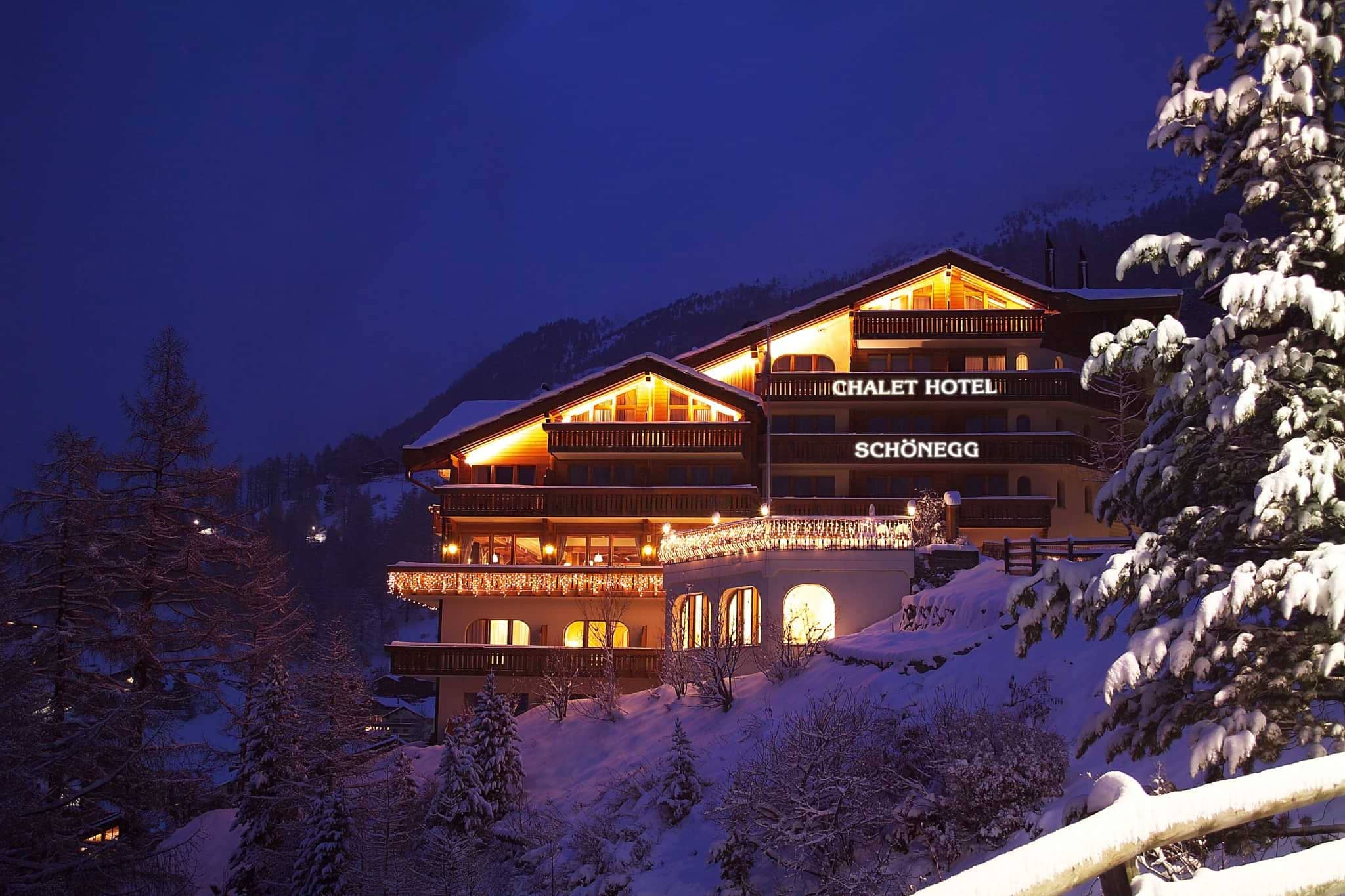Chalet exterior at night with private balconies and mountain hillside location