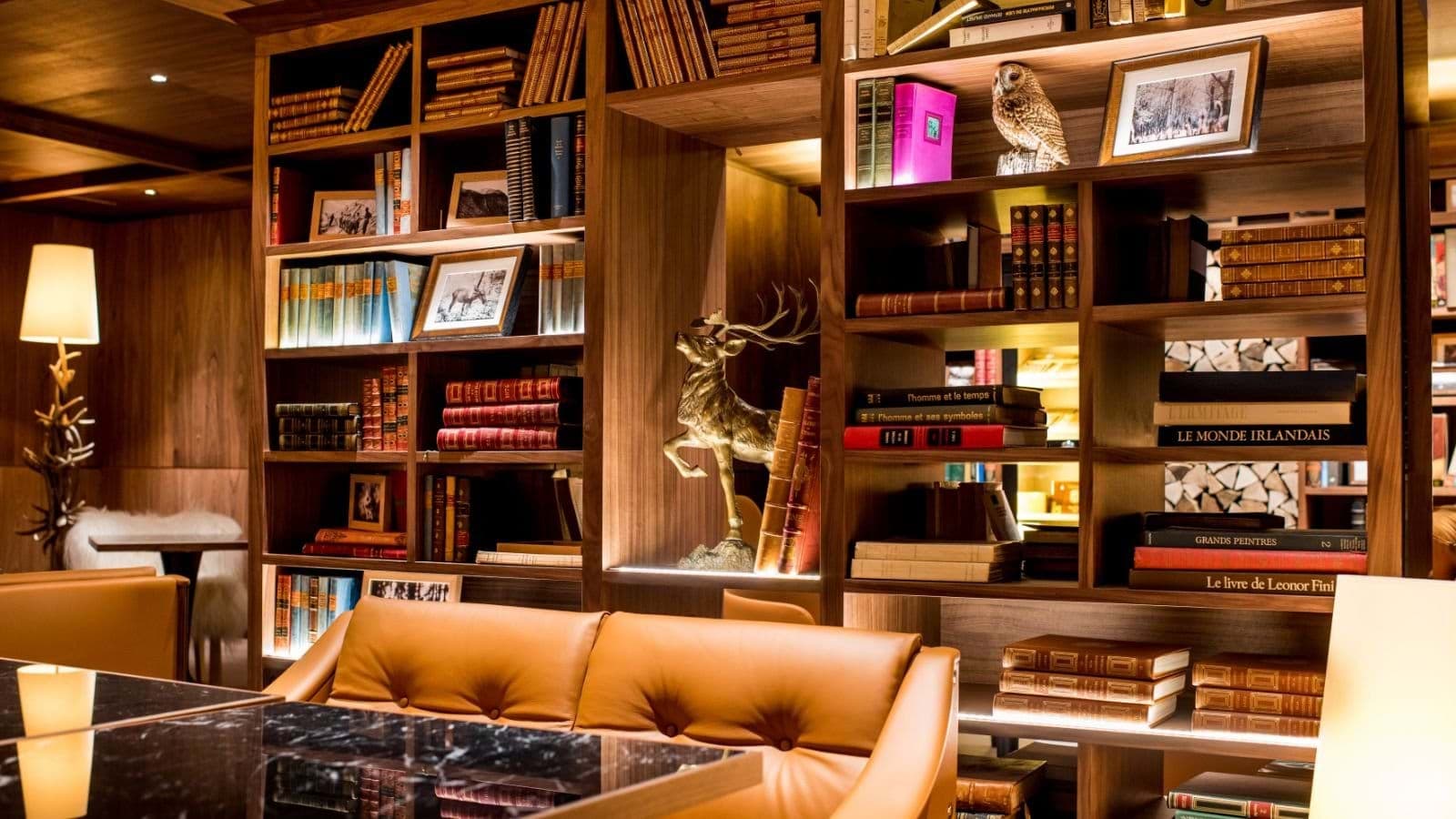 Library lounge with leather seating and floor-to-ceiling walnut shelving