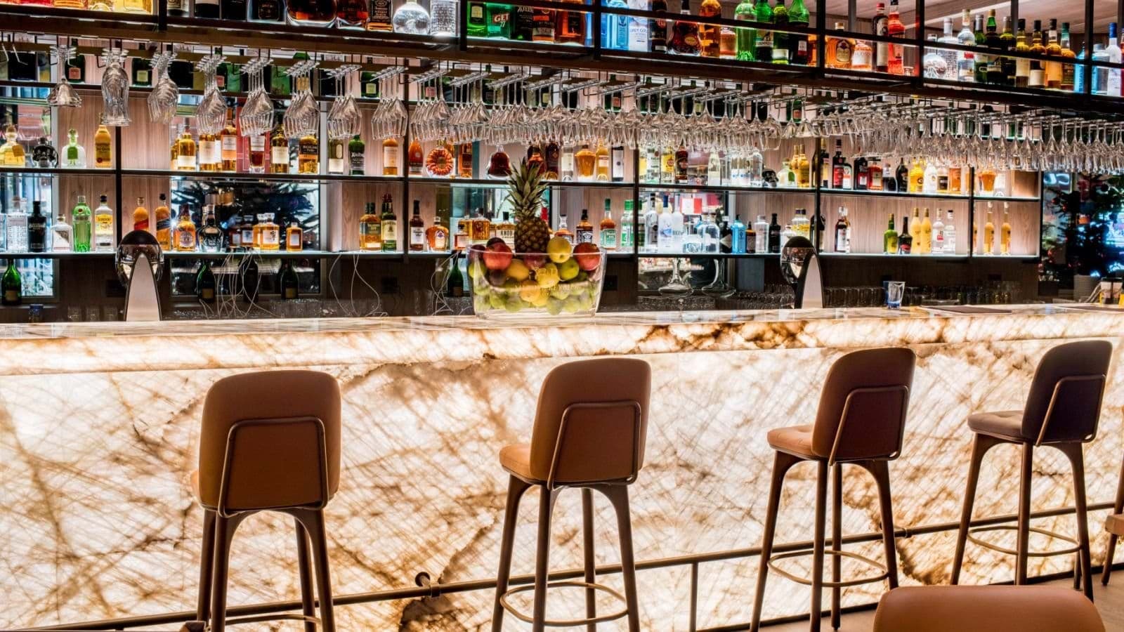 Backlit stone bar with leather stools and full liquor selection