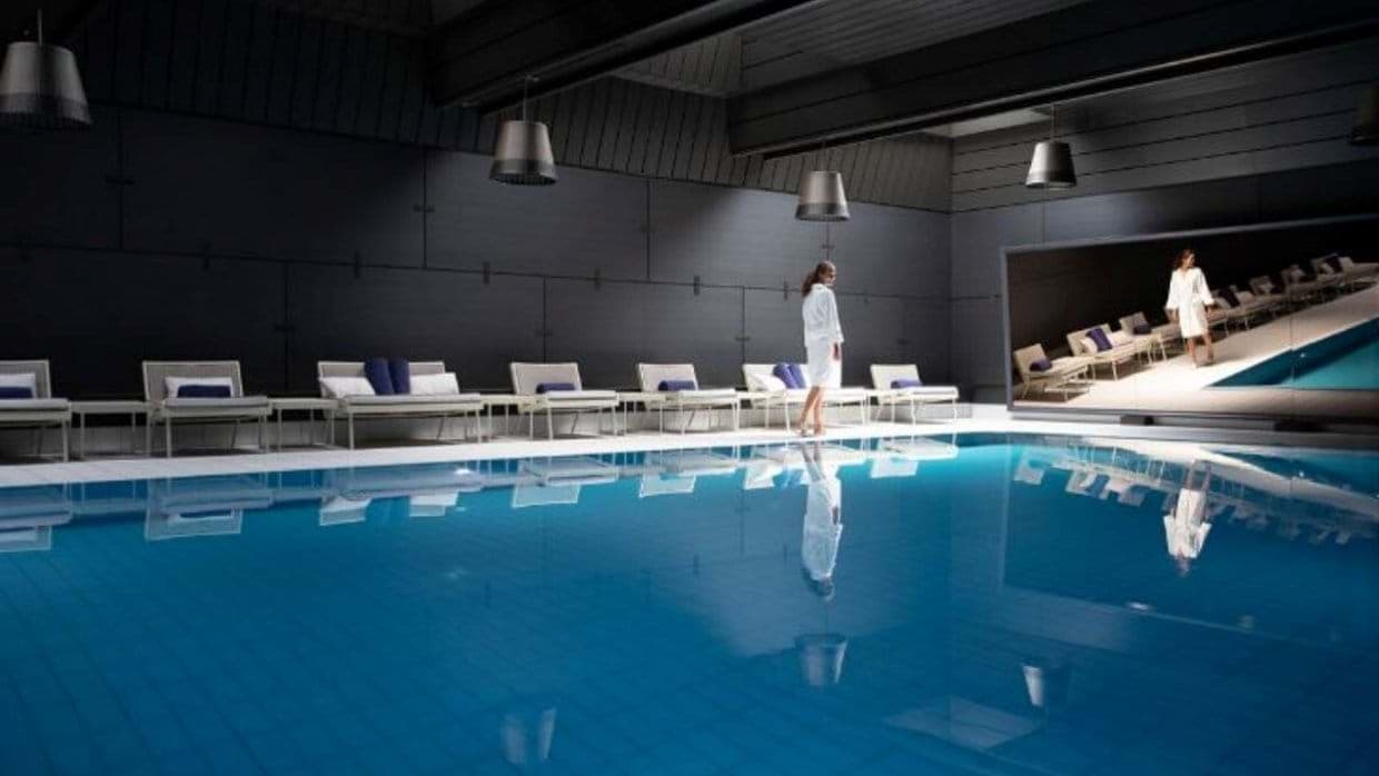 Indoor pool with poolside loungers and integrated wall cinema