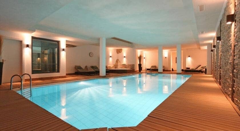 Indoor pool with wooden deck surround and lounge seating