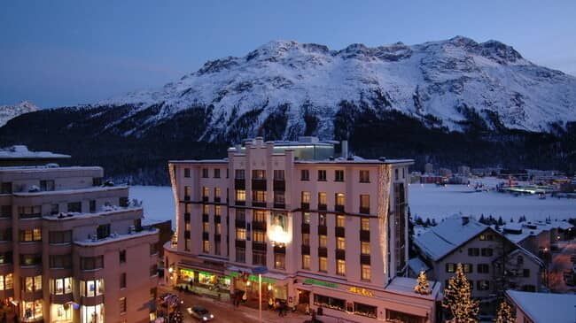 Hotel exterior at dusk with alpine mountain and lake views