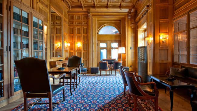 Wood-paneled library with leather seating and built-in bookcases