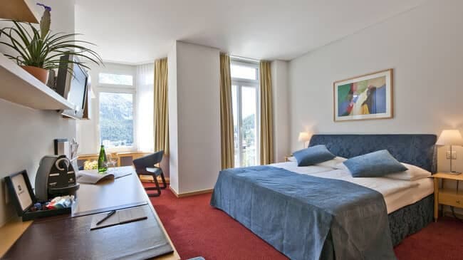 Bedroom with king bed, desk station, and mountain views
