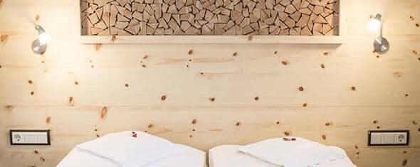 Bedroom featuring pine wood paneling, individual reading lamps, and bedside power outlets