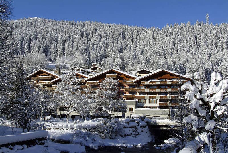 Alpine building exterior with private balconies; backing onto evergreen forest