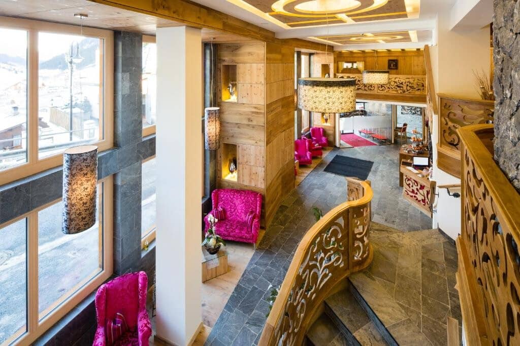 Two-story lobby with stone flooring, reception desk, and mountain views