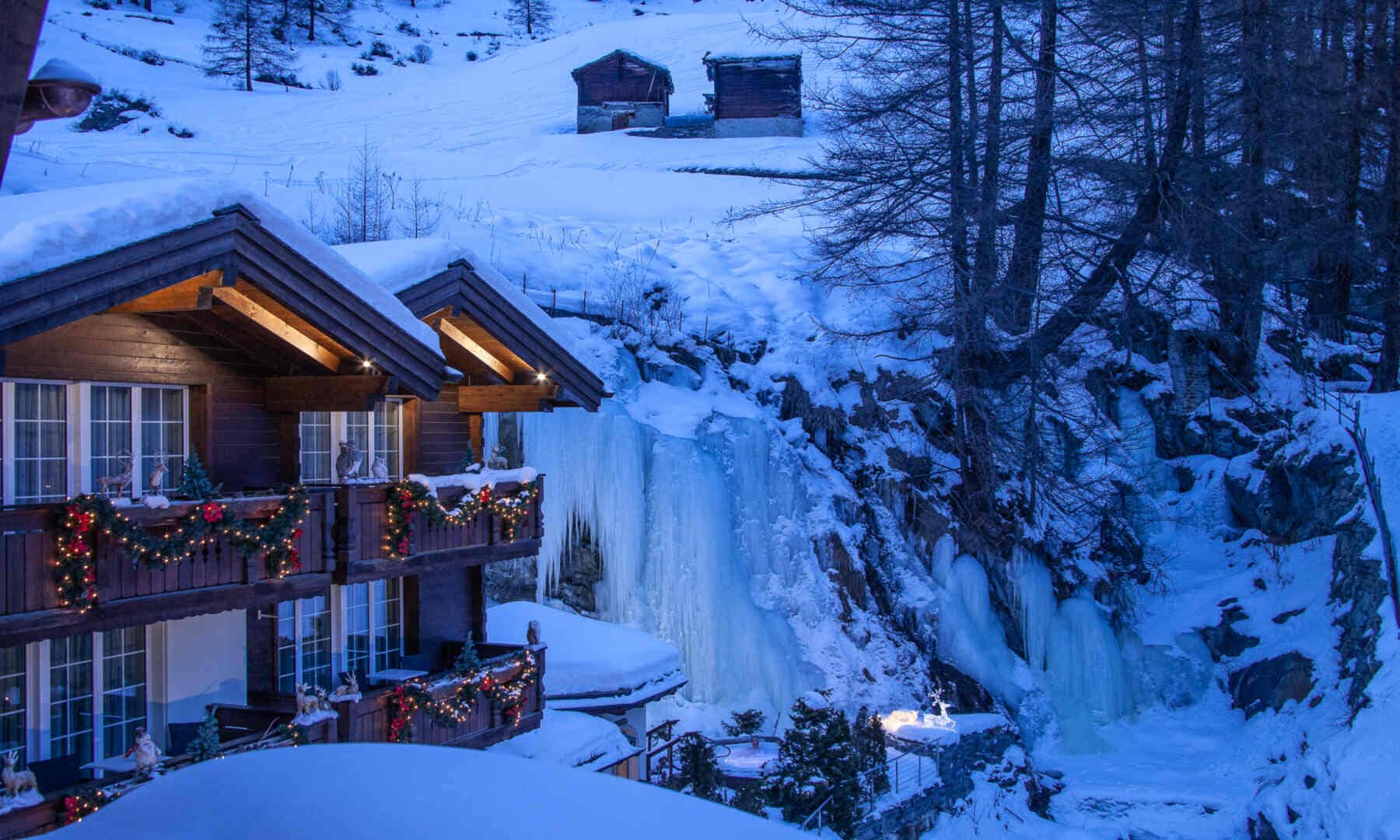 Chalet balconies overlooking private outdoor hot tub and frozen waterfall