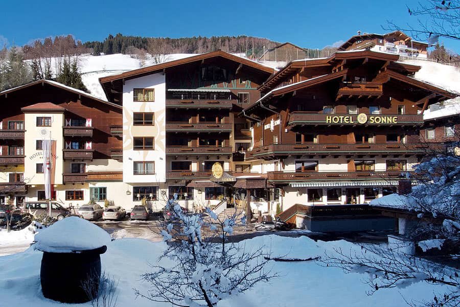 Alpine hotel exterior featuring private balconies and snowy mountain backdrop