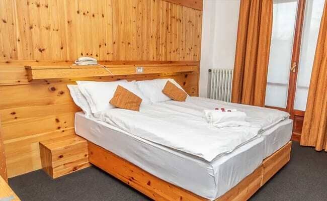 Wood-paneled bedroom with two twin beds pushed together and balcony access