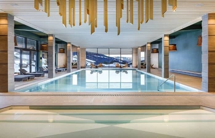 Indoor heated pool with mountain views and poolside lounge seating
