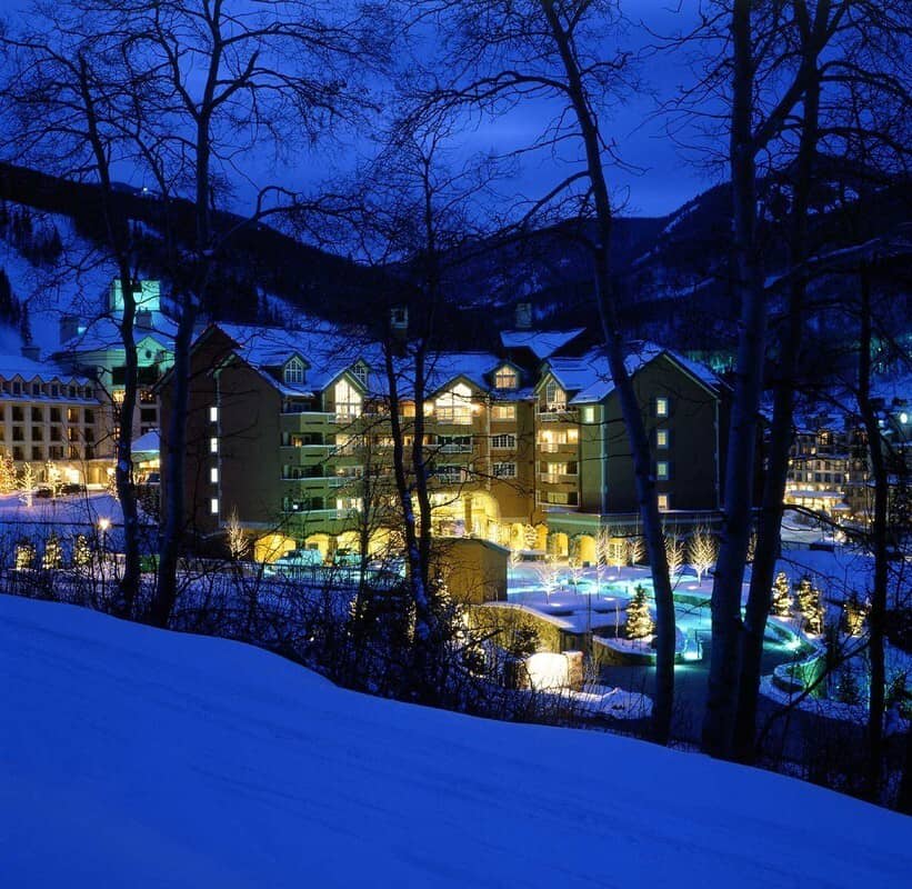 Ski-in/ski-out lodge exterior with illuminated pool and mountain views