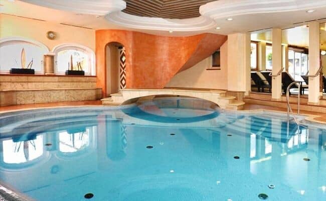 Indoor pool with integrated hot tub and poolside lounge seating