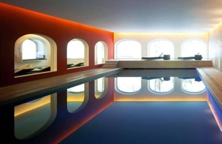 Indoor heated pool with arched lounge niches and terrace access
