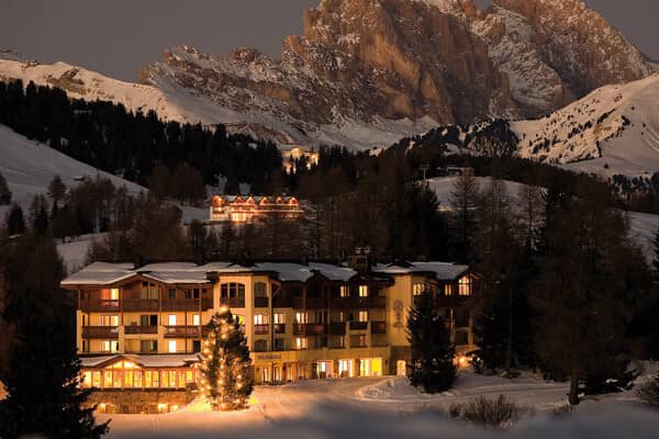Ski-in/ski-out lodge at dusk with illuminated balconies and mountain backdrop