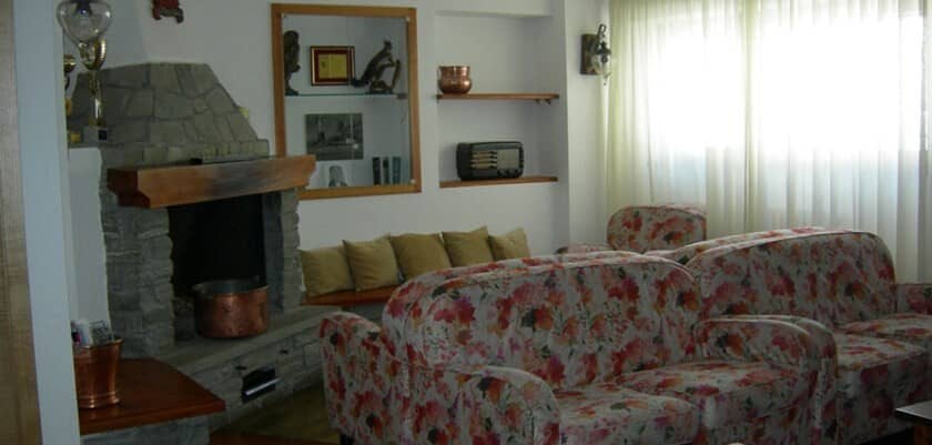 Living room with wood-burning stone fireplace and floral sofa seating