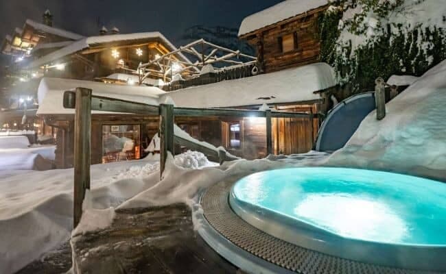 Outdoor hot tub with turquoise water; heated in winter snow setting