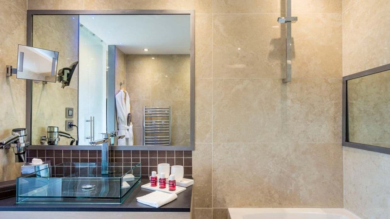 Bathroom with glass vessel sink, hairdryer, and heated towel rail