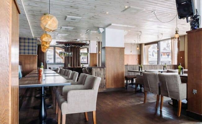 Dining area with flexible table configurations and upholstered armchairs