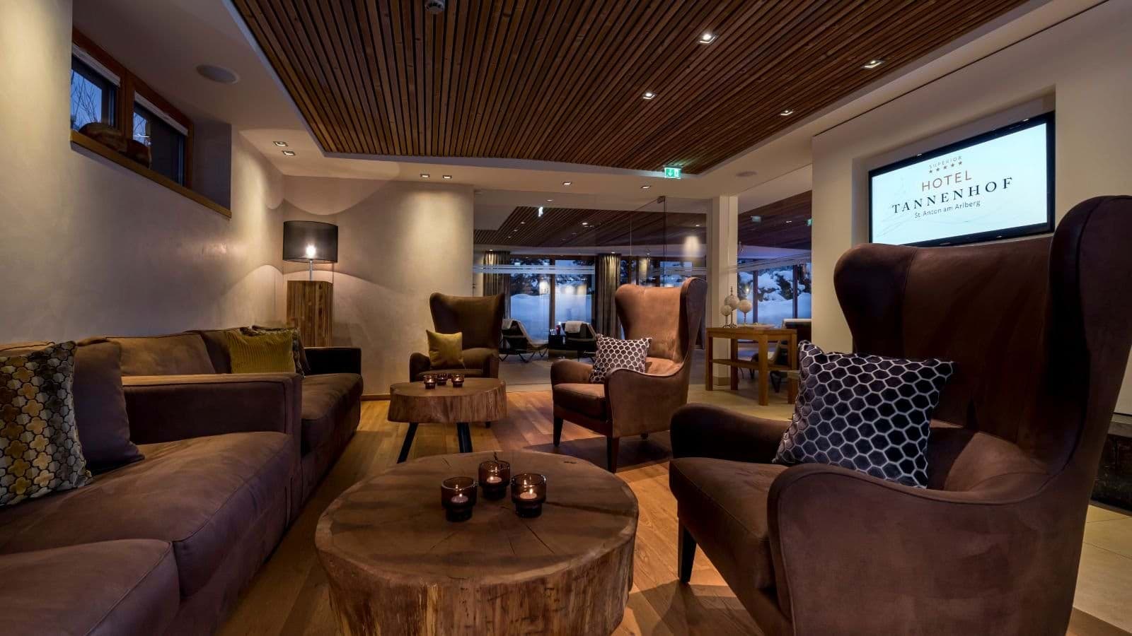 Lounge with wood-slat ceiling, leather wingback chairs, and wall-mounted TV