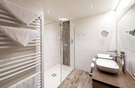 Bathroom with walk-in shower, dual sinks, and heated towel rail