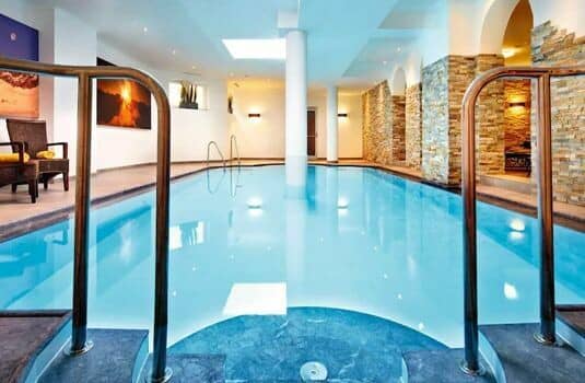 Indoor swimming pool with stone feature walls and lounge seating