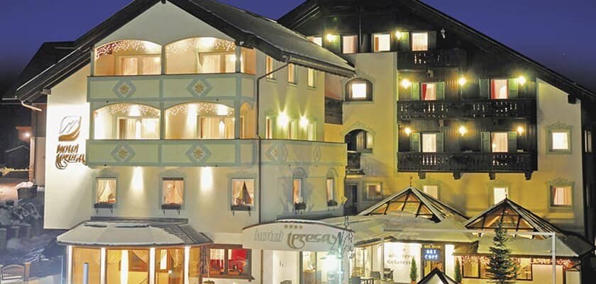 Chalet exterior at night with private balconies and glass-roofed terrace