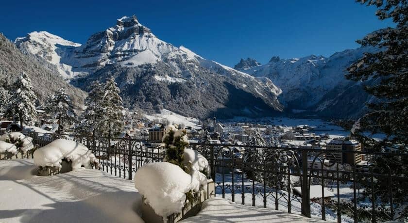 Private balcony with wrought-iron railing overlooking alpine village and mountain peaks