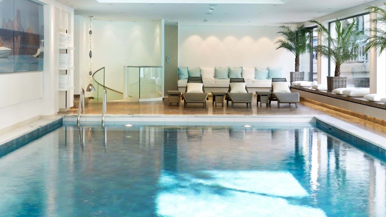 Indoor heated pool with lounge seating and glass-enclosed spiral staircase