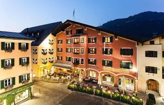 Alpine property exterior with ground-floor restaurant and mountain backdrop