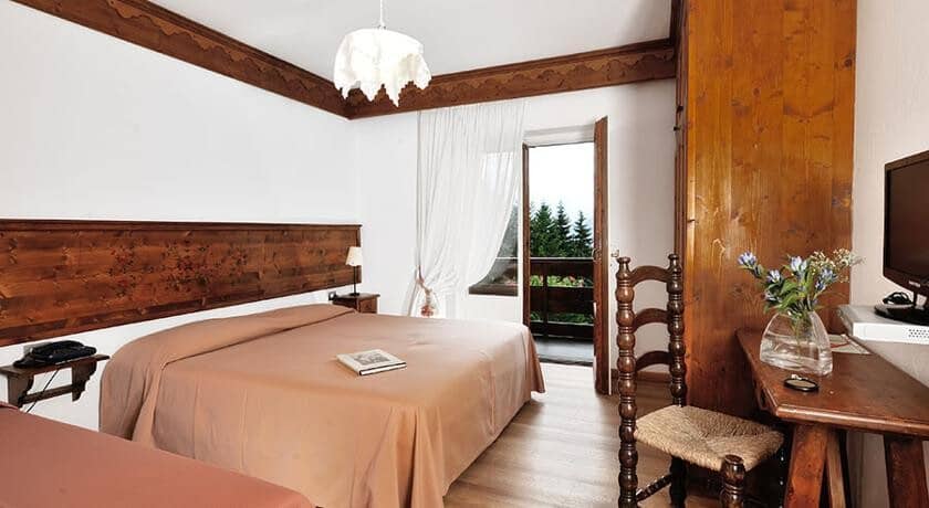 Bedroom with wood-paneled walls and balcony access to pine forest