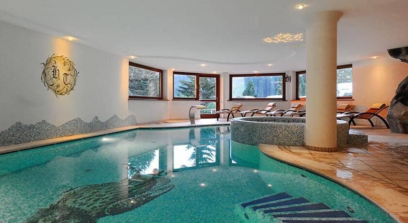 Indoor pool with circular hot tub and poolside lounge seating
