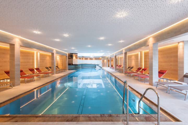 Indoor lap pool with ladder entry and poolside lounger seating