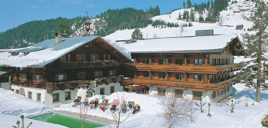 Alpine lodge exterior with outdoor pool and mountain backdrop