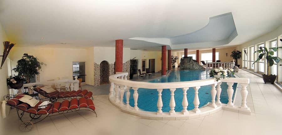 Indoor pool with rock waterfall feature and cushioned lounge seating