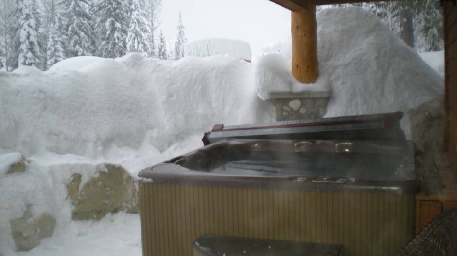 Covered outdoor hot tub with forest views and stone accents